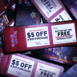 A pile of 2x6 2-part admission tickets for a haunted house. The focus of the image is the full-color backside of the ticket, which includes coupons for the attendees to redeem at the haunt's gift shop